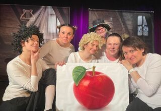 Aktorzy zgromadzeni wokół obrazu z jabłkiem