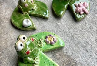Trzy ceramiczne zielone żabki na szarym blacie