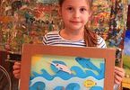 Dziewczynka trzyma pracę w ramce przedstawiającą świat podwodny