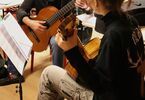 Uczennica podczas nauki gry na gitarze z instruktorem